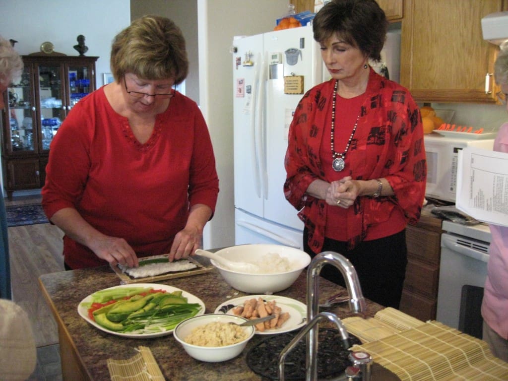Betsy demonstrates the fine art of sushi making while Maureen Callaway is an attentive student.